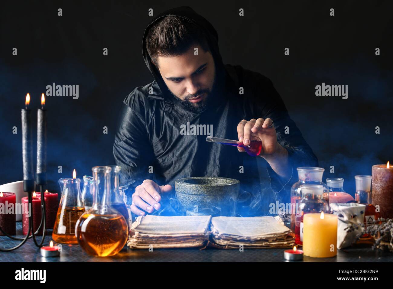 Male alchemist making potion on dark background Stock Photo