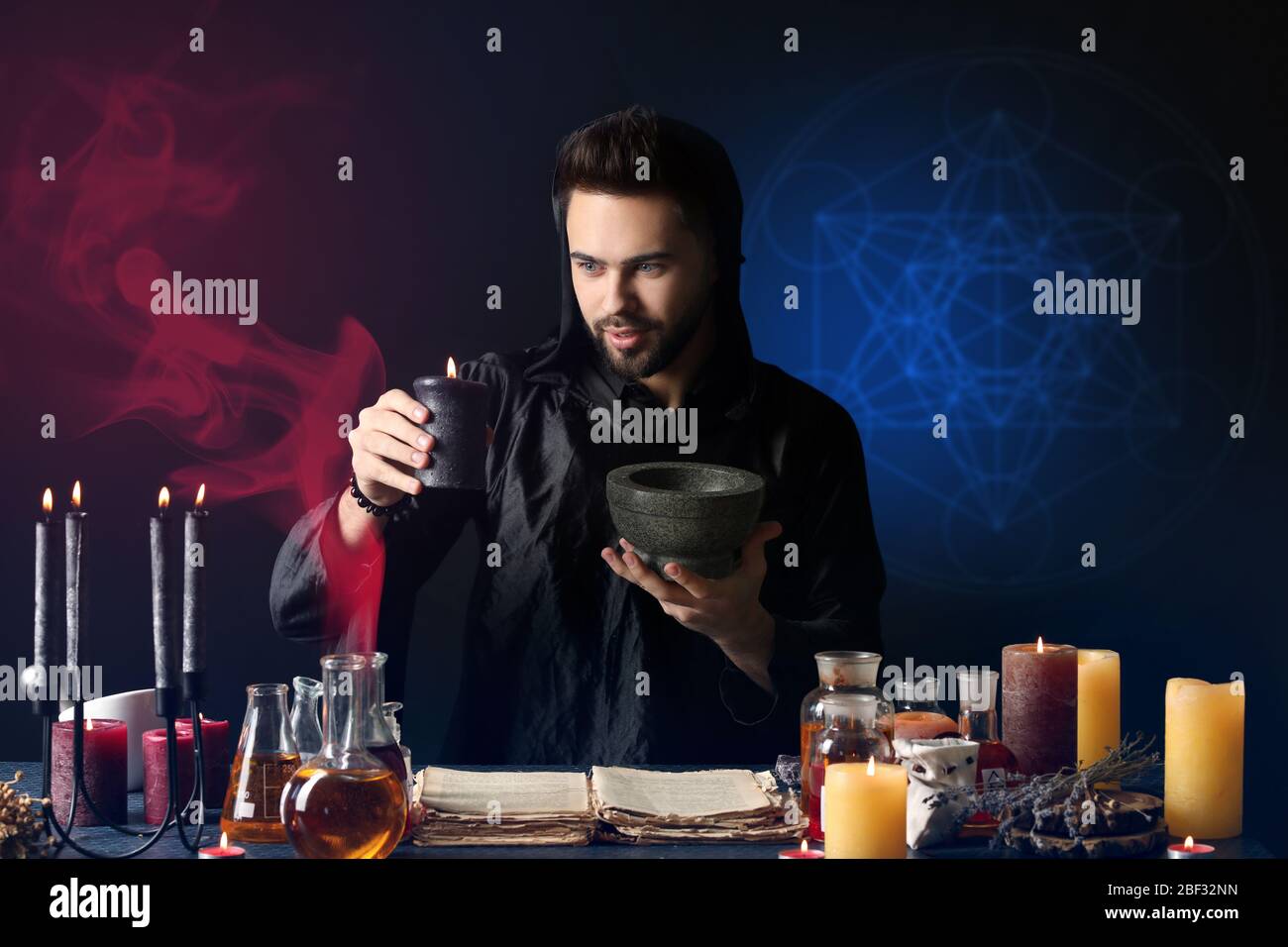 Male alchemist making potion on dark background Stock Photo