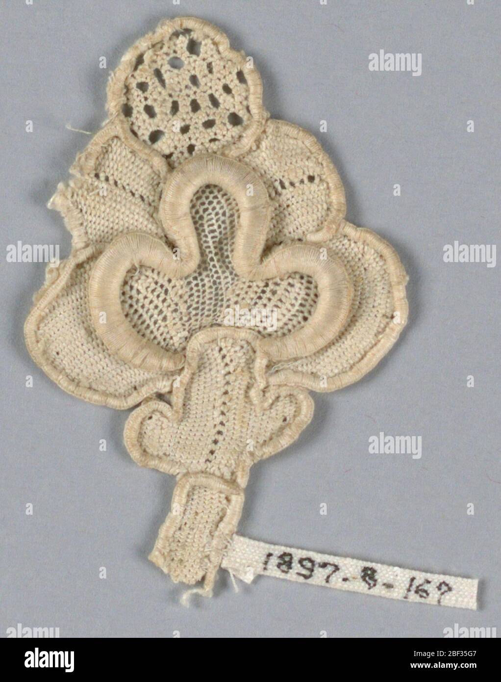 Fragment. Fragment of raised lace with a highly conventionalized design of a pomegranate bud with an openwork tip. Stock Photo