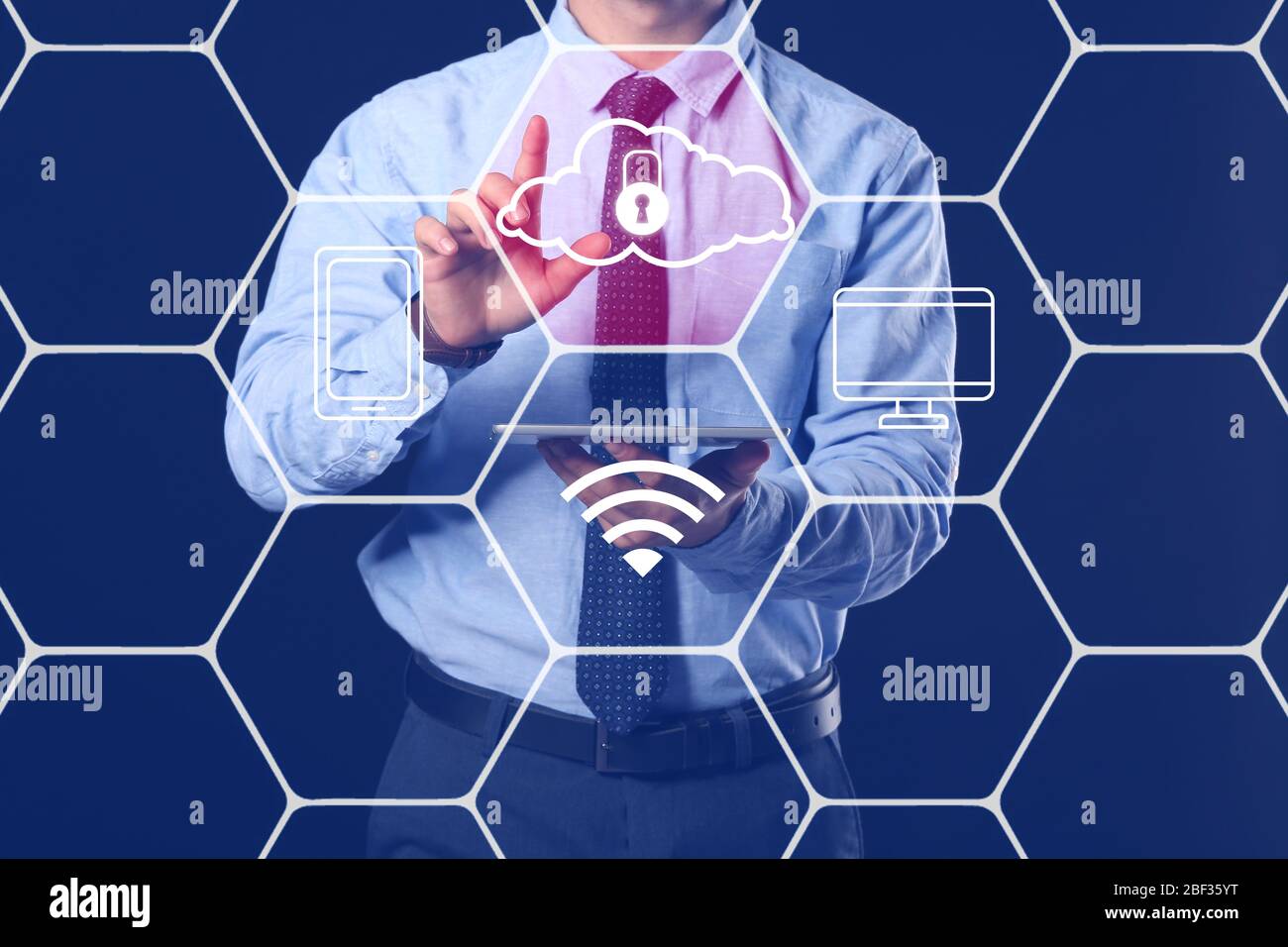 Businessman with tablet computer using cloud storage service on dark background Stock Photo