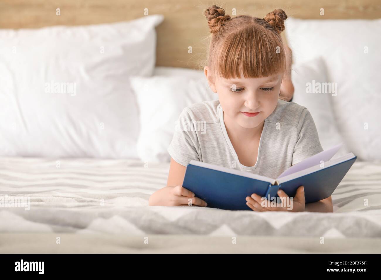 Cute little girl reading book at home Stock Photo - Alamy
