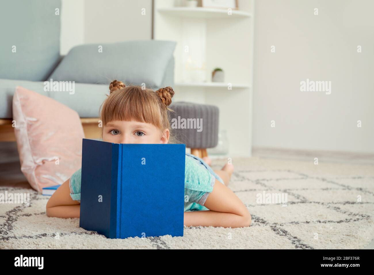 Cute little girl reading book at home Stock Photo - Alamy
