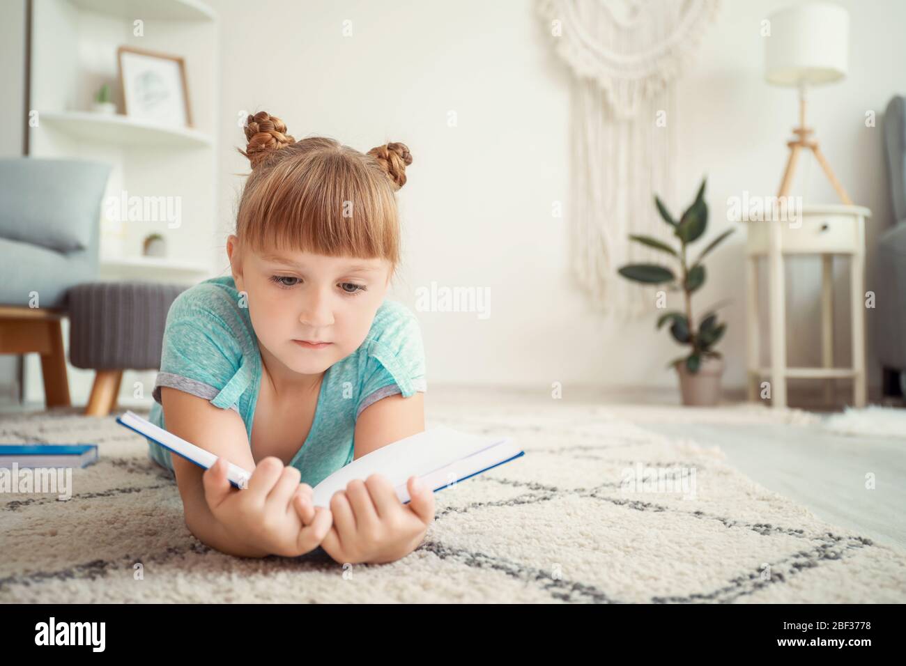 Cute little girl reading book at home Stock Photo - Alamy