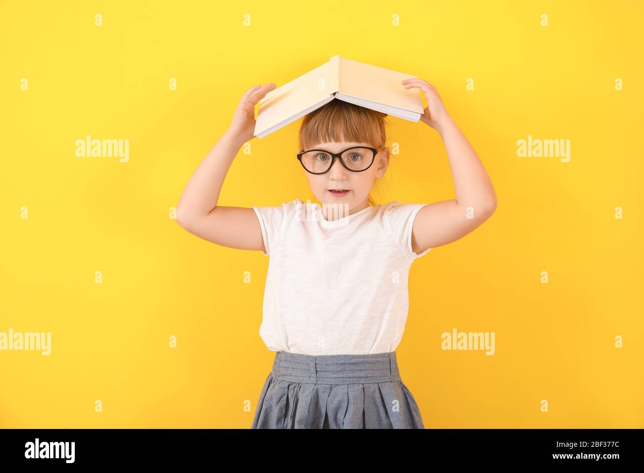 Cute little girl with book on color background Stock Photo - Alamy