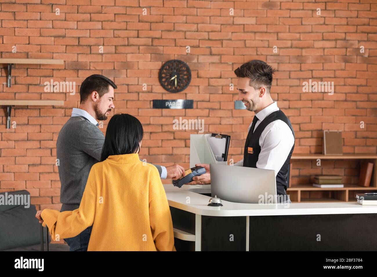 Couple paying for hotel room at reception Stock Photo Alamy