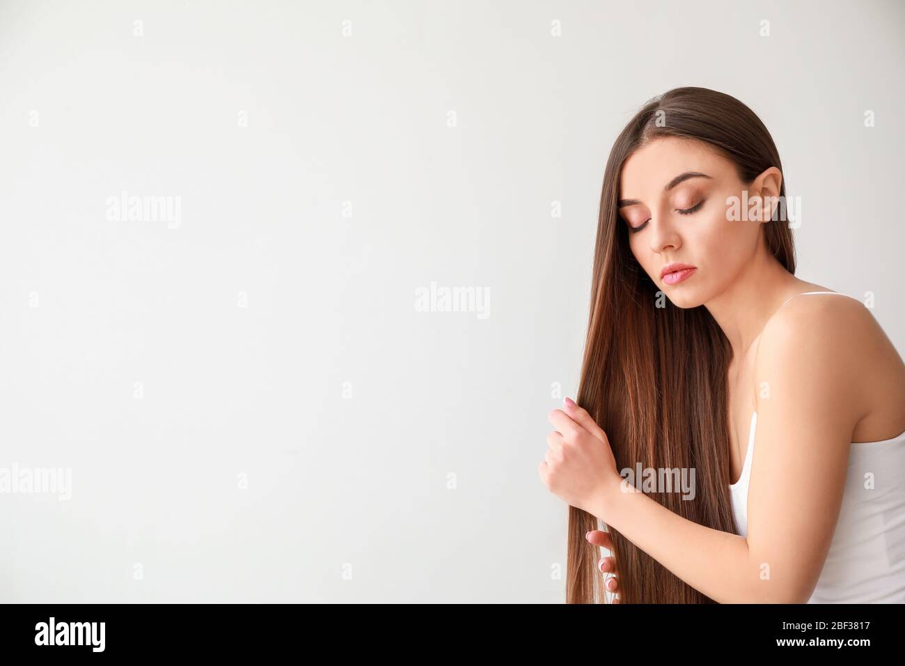 Beautiful woman with healthy long hair on white background Stock Photo ...