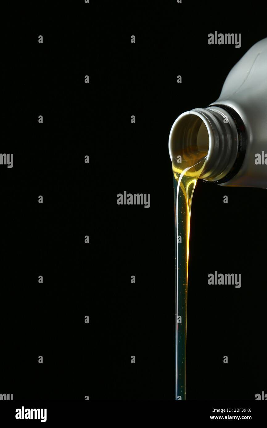 Pouring car oil on dark background Stock Photo - Alamy