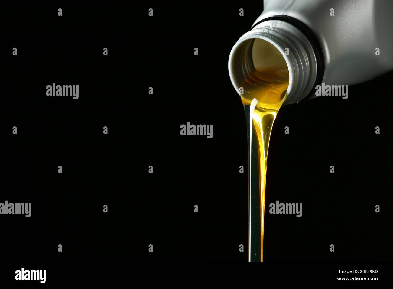 Pouring car oil on dark background Stock Photo - Alamy