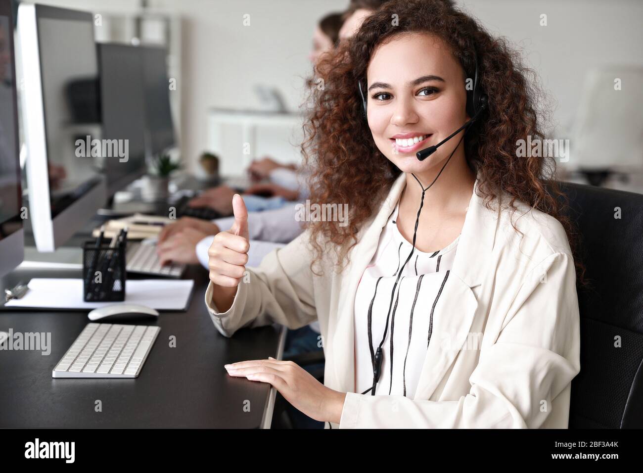 Portrait of female technical support agent showing thumb-up in office ...