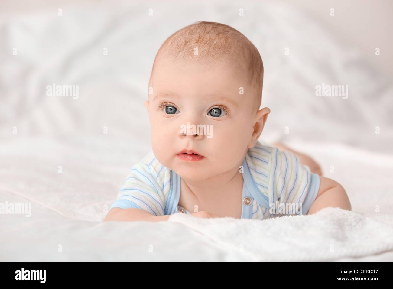 Portrait of cute little baby lying on bed Stock Photo - Alamy