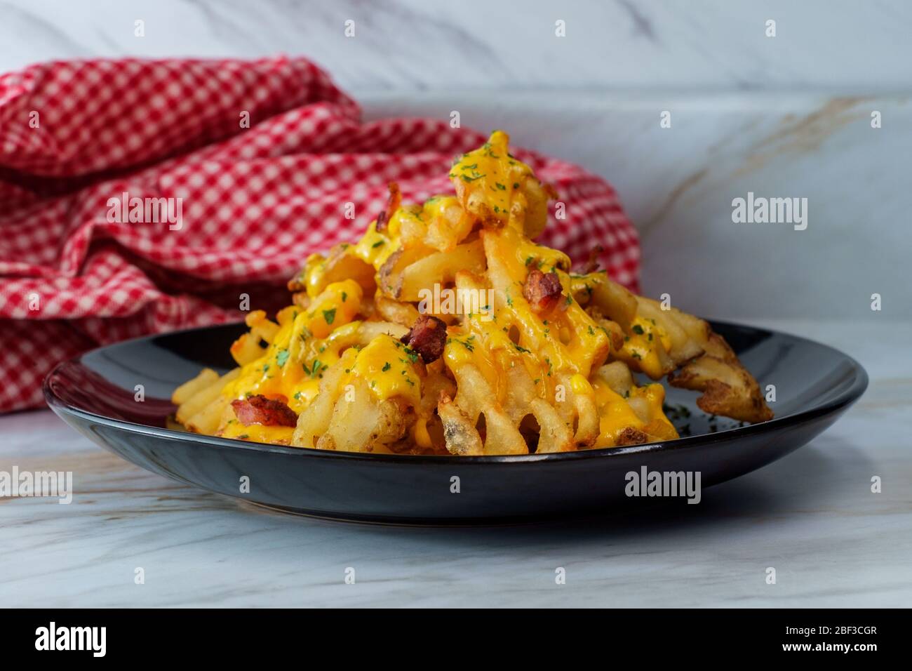 Crispy waffle fries loaded with bacon and melted cheddar cheese sauce Stock Photo
