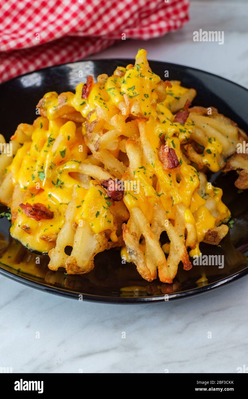 Crispy waffle fries loaded with bacon and melted cheddar cheese sauce Stock Photo