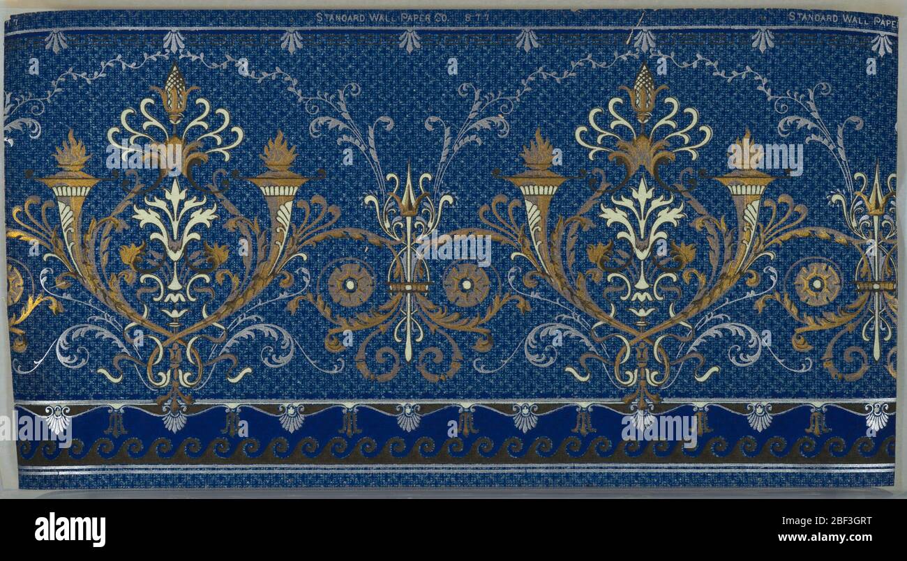 Frieze. Alternating large and small foliate medallions with torches and spear, connected by waving foliate scrolls and foliate vining. Bottom has scrolls, waves, and floral motifs. Top has key pattern and floral motif. Background is a white and blue grid. Stock Photo
