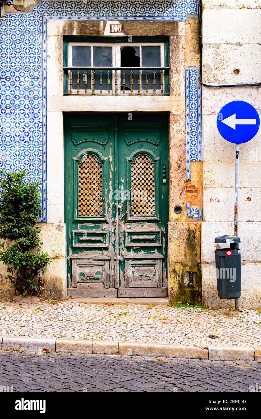 Antique green doors locked with a chain and a building with blue and green tiles in Lisbon Stock Photo