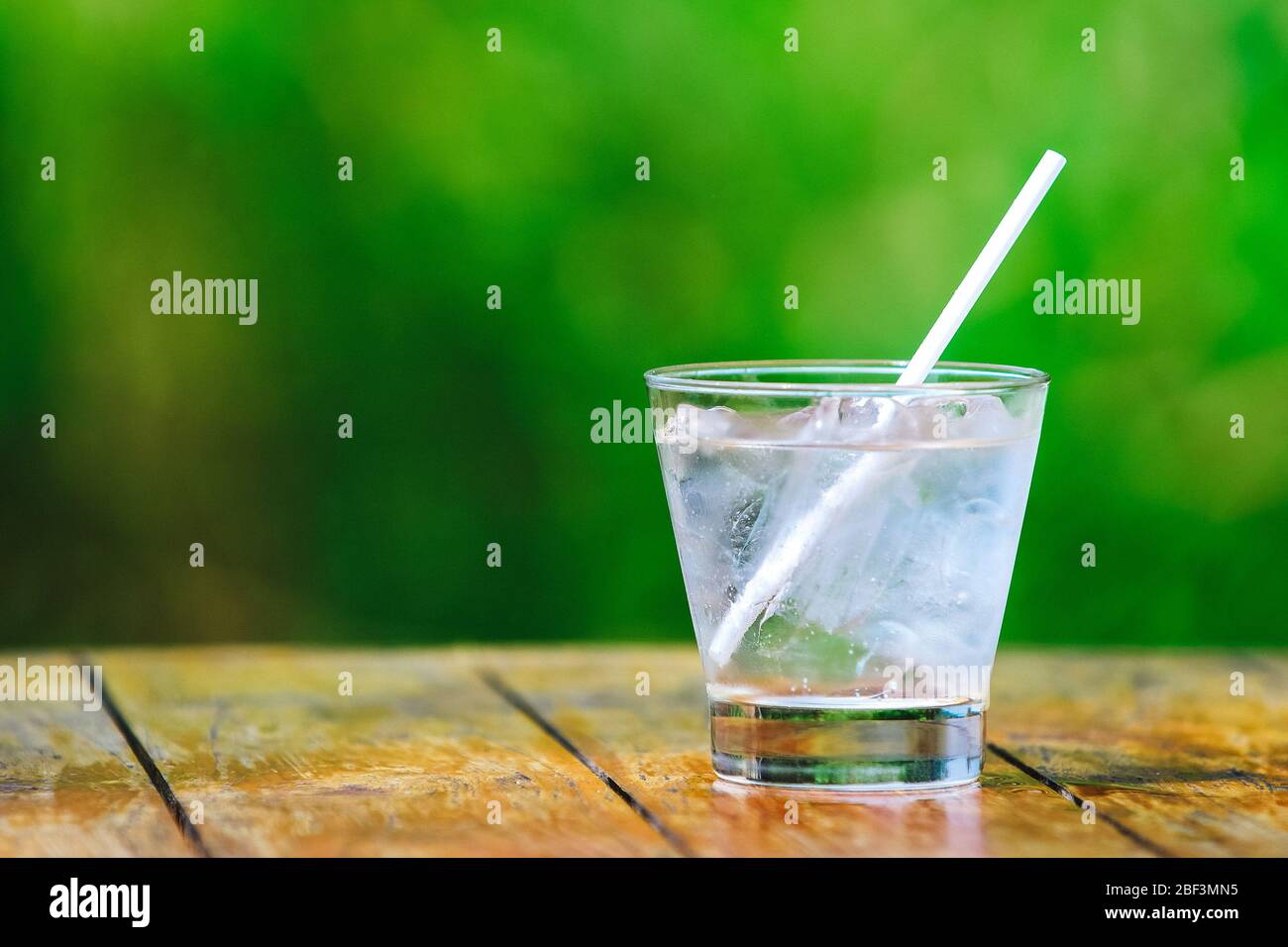 Glass glass. Mineral water with ice. Cocktail straw. A green background ...