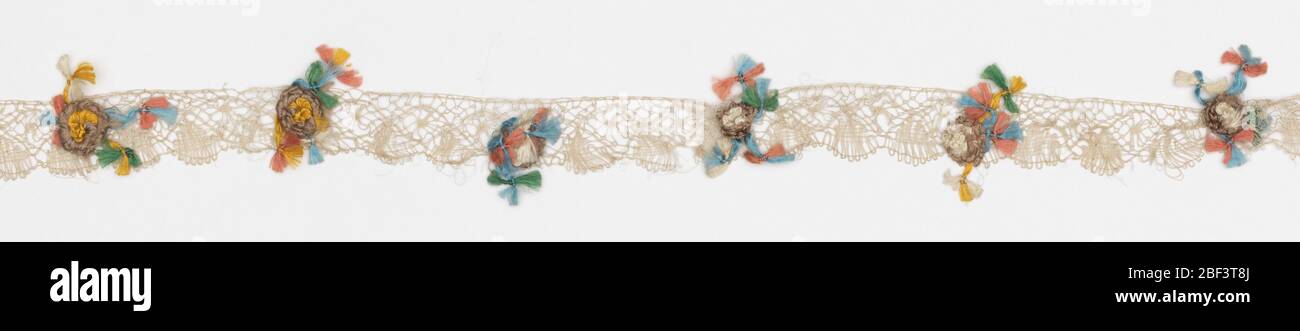 Edging. Lace band with floss flowers sewn at intervals. Loosely worked undyed silk bobbin lace with a scalloped edge dotted with single flowers and a few small knotted tassels of polychrome silk floss sewn at regular intervals. Stock Photo