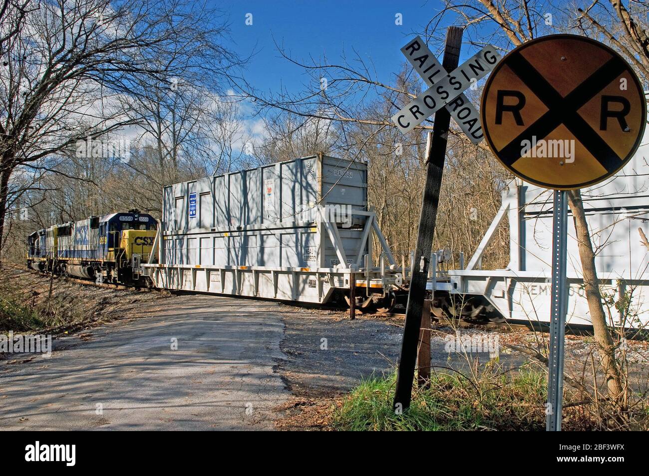 2006 CSX freight train engine pushing railroad cars at a rural railroad crossing Stock Photo