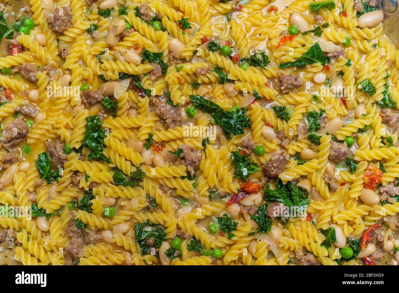 Cooking Italian kale sausage rotini pasta in white wine butter garlic