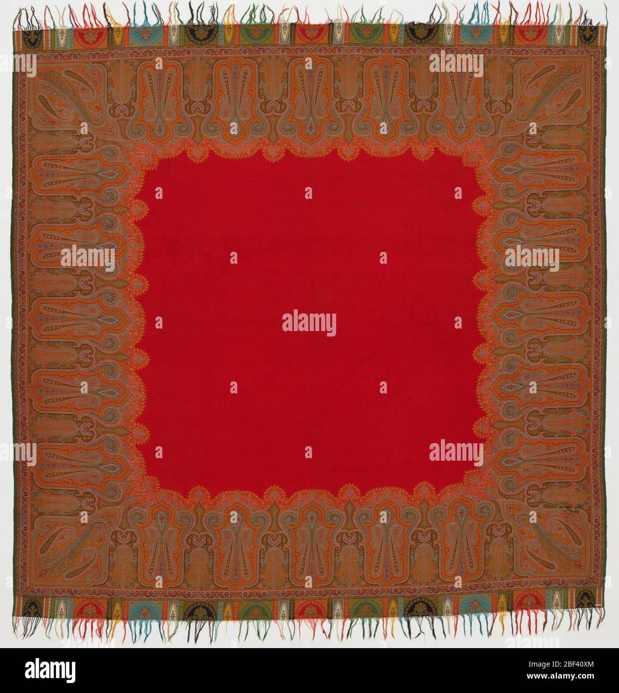 Shawl. Shawl with a red center and a multicolored cone and lotus border design. Fringed on two ends. Long sides have a narrow green border. Stock Photo