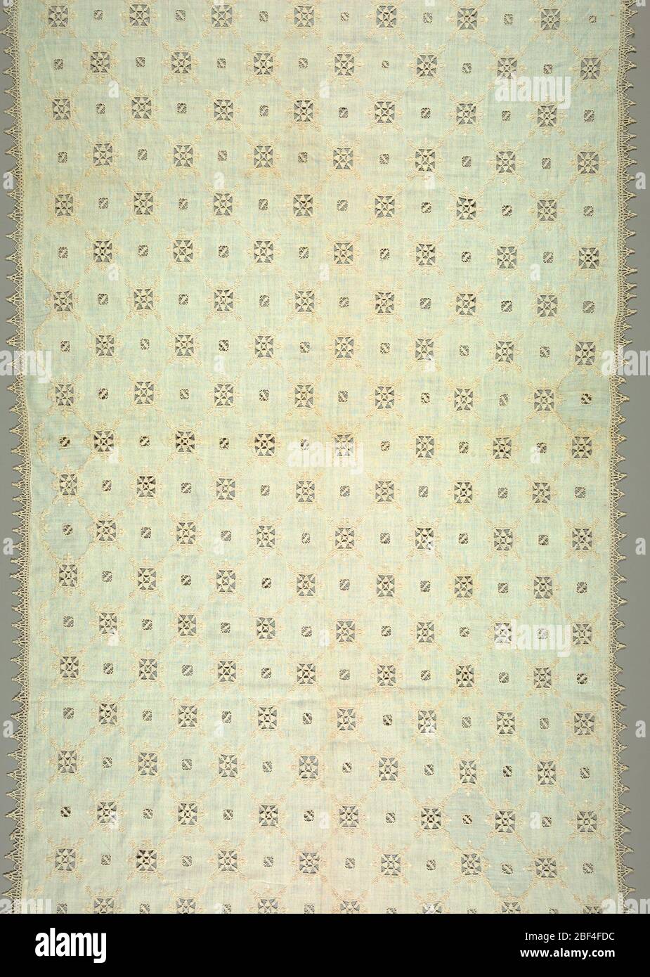 Cover. Cover with a detached arrangement of square designs of cutwork connected with white embroidered lines forming a trellis pattern. Squares framed in white embroidered design in spear-shaped patterns. Edging of pointed bobbin lace. Stock Photo