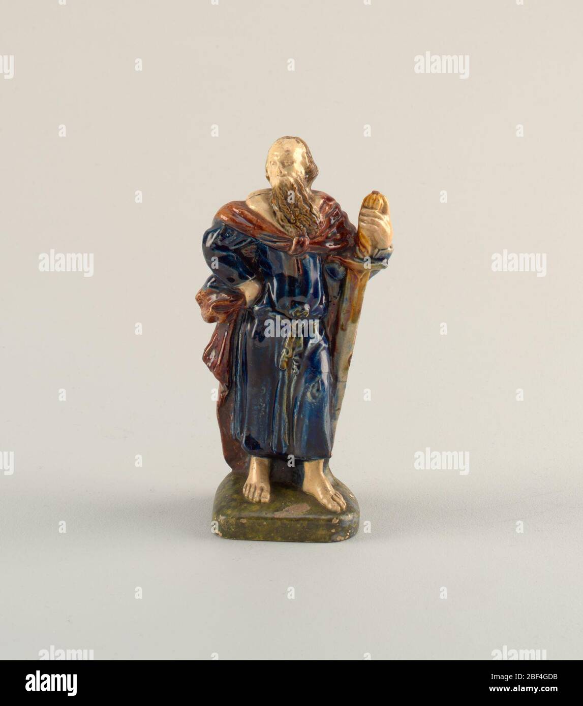 St Paul. Standing figure of Saint Paul leaning on a large broadsword, head turned toward the figure’s right. Right hand on hip. Blue robe, brown cape with white collar. On mottled green plinth. Stock Photo