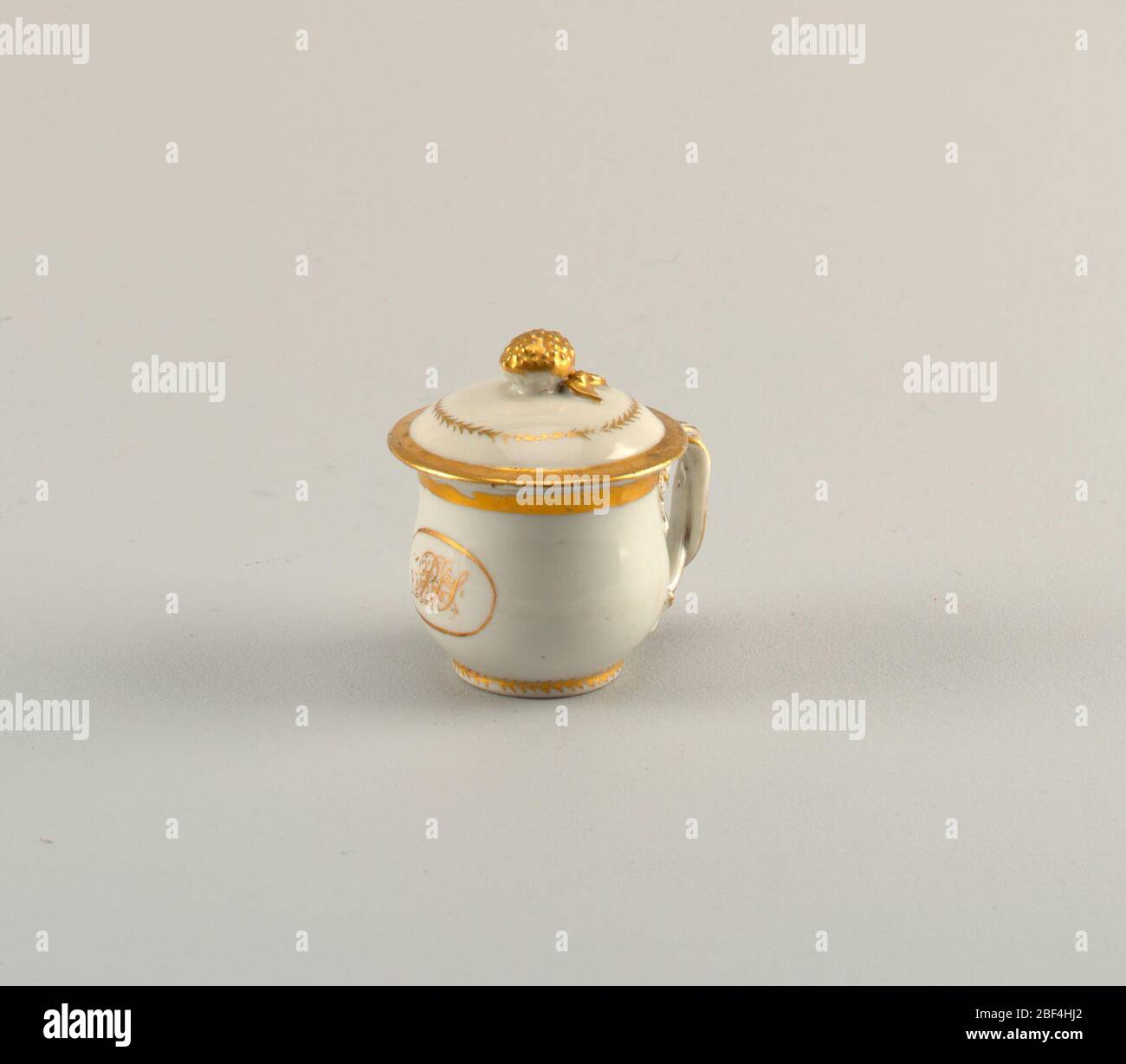 Covered Cup. Porcelain cup and cover with a decorated handle and gilt initials belonging to a serving set. Stock Photo