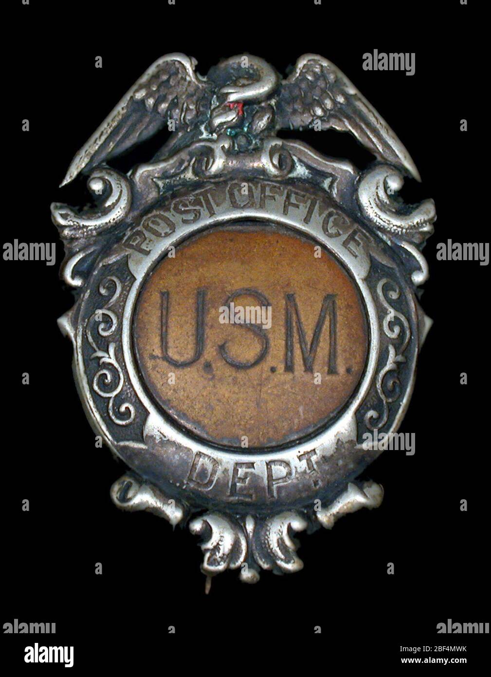 Guard chest badge. United States Post Office Department guard badge with vertical hinged pin and clasp on verso. Spread eagle surmounts medallion with skirt. Upper portion marked 'POST OFFICE'; lower portion inscribed 'DEPT'; medallion center bears the letters 'U.S.M.' Stock Photo