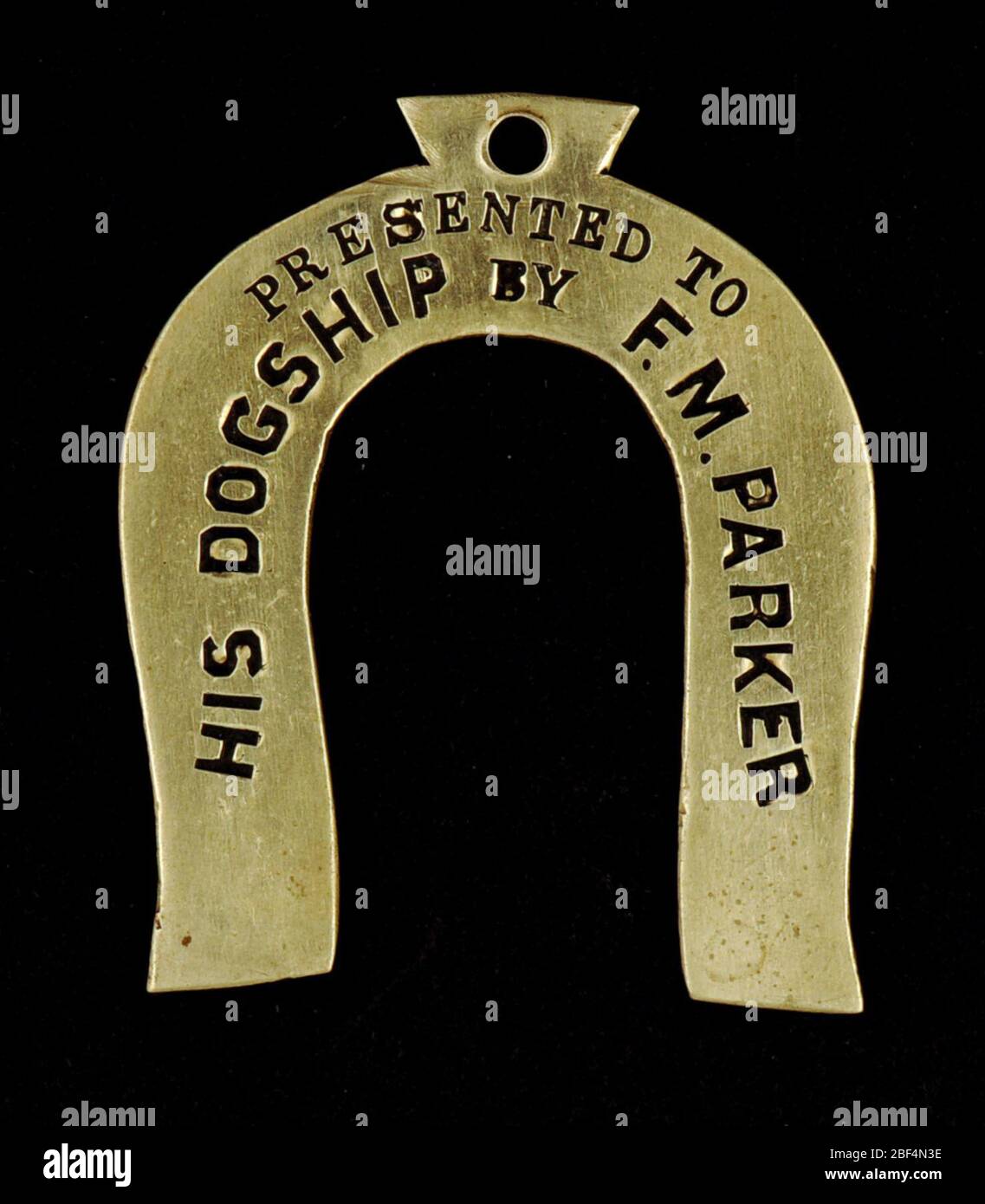 Baltimore and Grafton Railway Owney tag. This horseshoe-shaped metal tag includes the inscription that it was presented to “His Dogship by F.M.Parker.” The reverse of the tag includes the date April 20, 1892, and the railway line, the Baltimore and Grafton Railway Post Office (RPO) car. Stock Photo