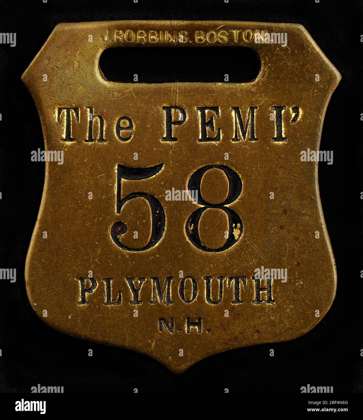 Plymouth New Hampshire Owney tag. This shield-shaped metal tag is marked “The Pemi, 58, Plymouth, NH.” The exact origin of this tag is unknown. It commemorated Owney’s trip to Plymouth, New Hampshire, and possibly a night’s stay at the city’s Pemi Hotel. Stock Photo