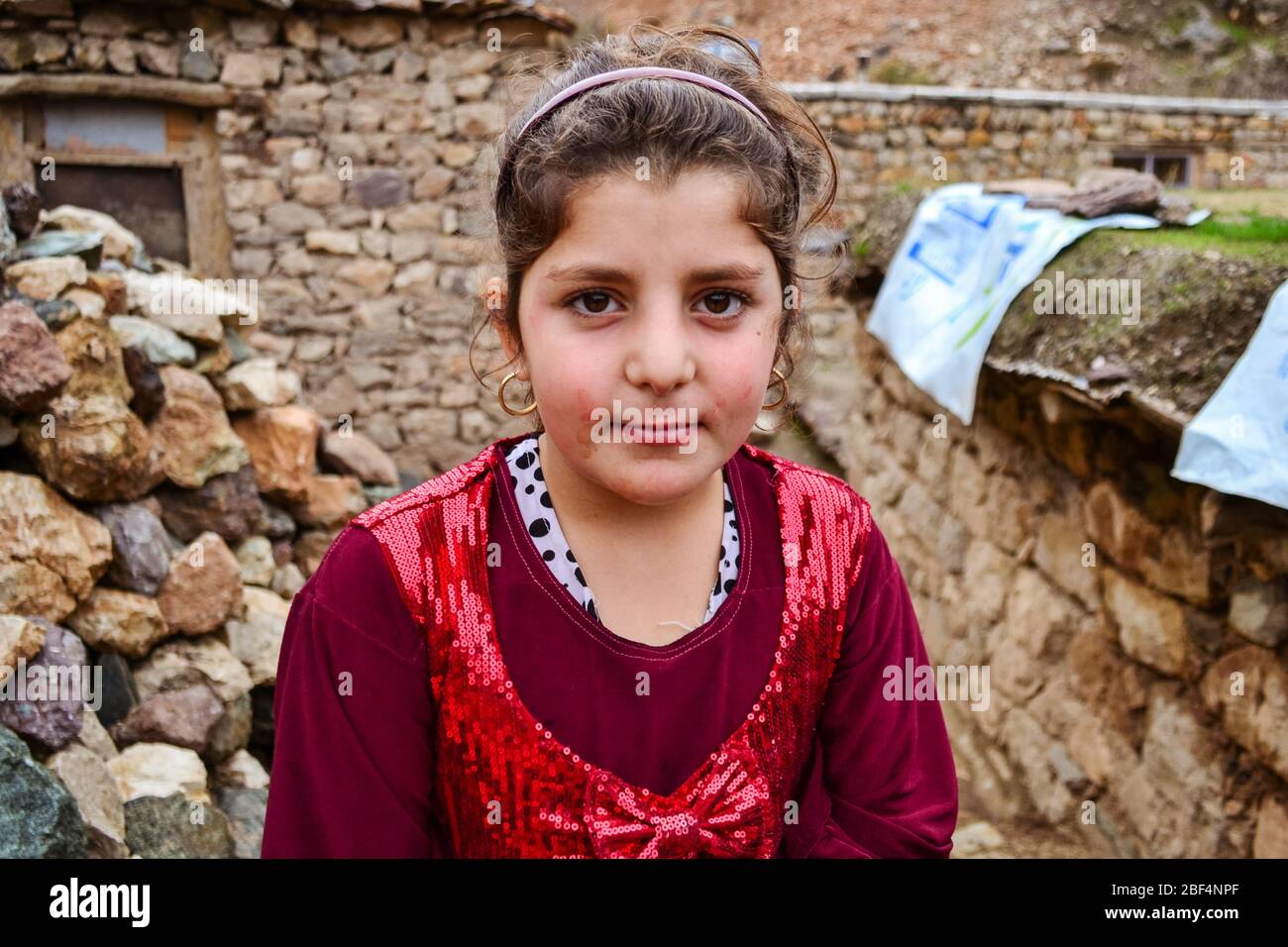 Palangan, Iranian Kurdistan - November 15, 2013: Portrait of cute Kurdish girl with red dress posing in old Palangan town Stock Photo