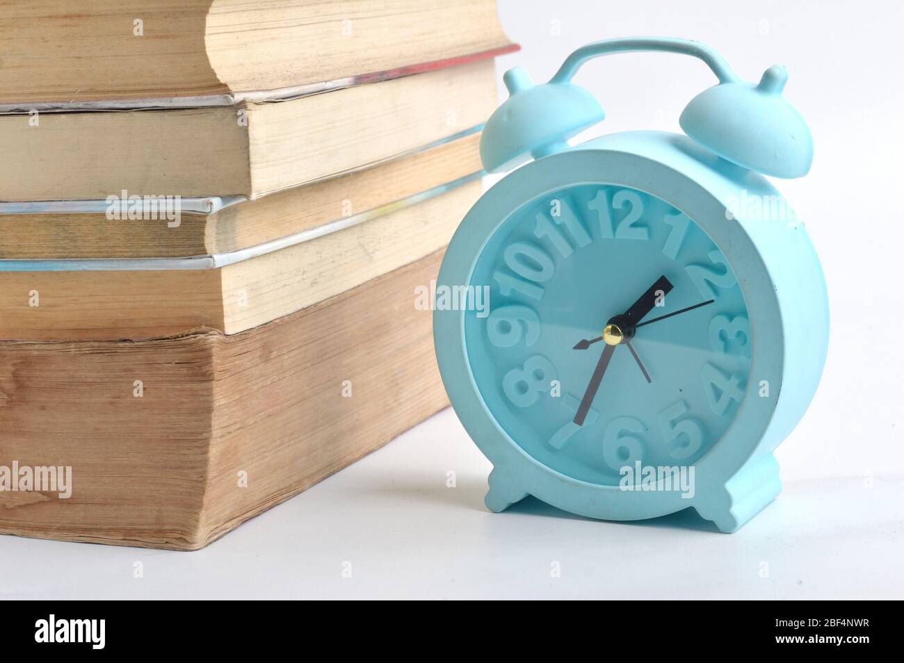 stack of books and a blue alarm clock on white background Stock Photo ...