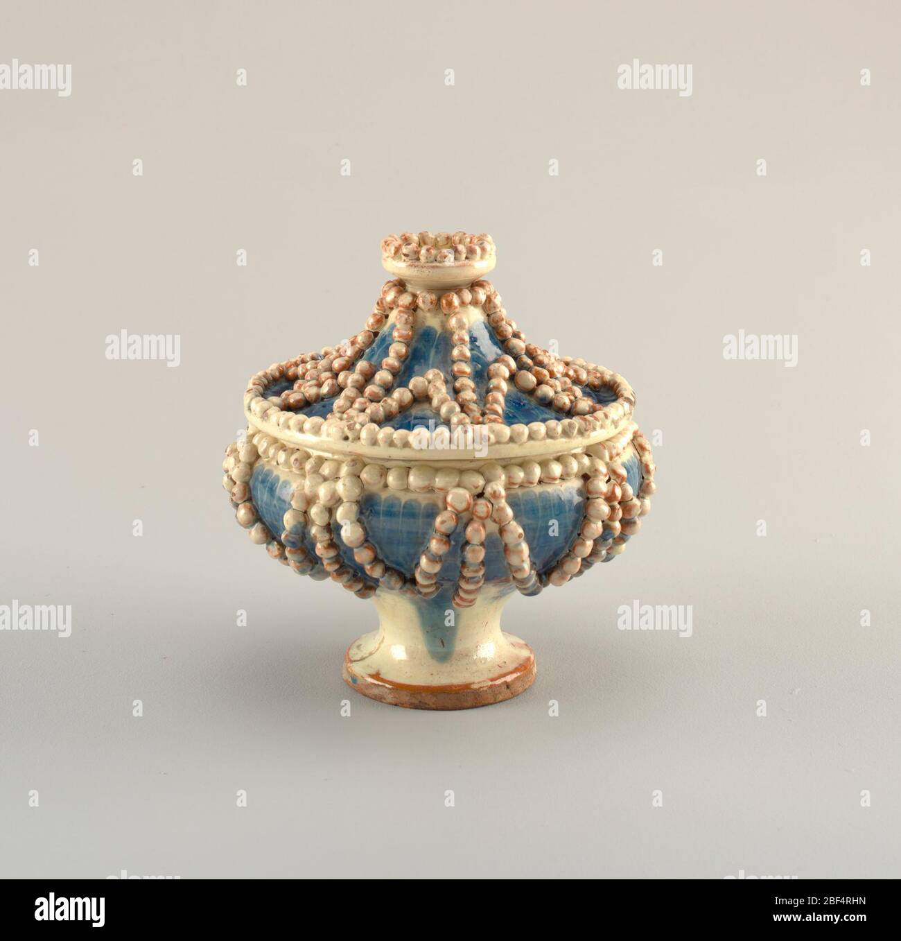 Bowl and lid. Blue footed bowl with star pattern of white pearls all over. Finial made up of crown of pearls. Stock Photo