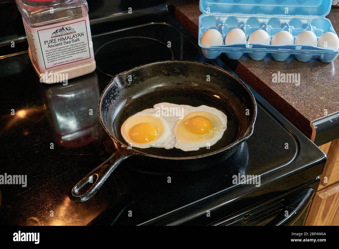 Breakfast Two sunny side up eggs frying in cast iron skillet Stock Photo