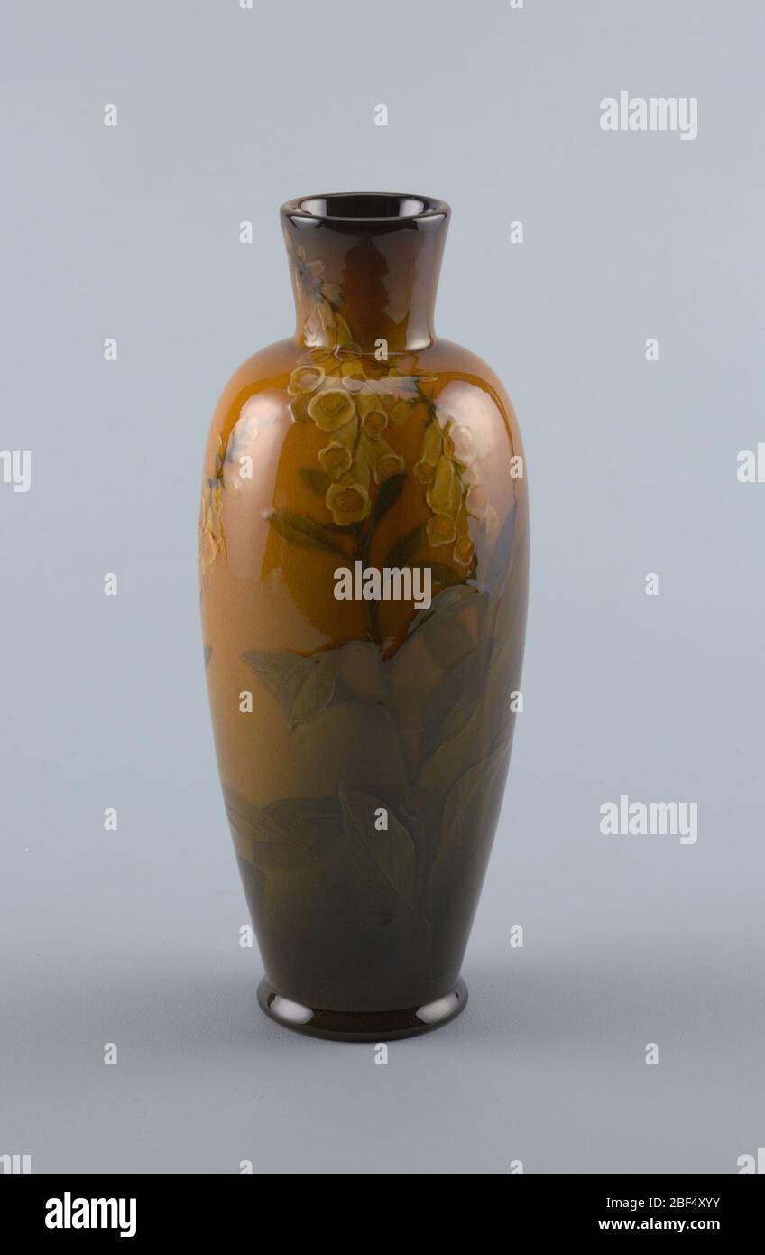 Vase. Cast white clay body. Elongated ovoid body with raised cylindrical neck, slightly flaring; circular foot. Underglazed slip-decoration on front with three stalks of golden yellow foxgloves, with green leaves and stems. Stock Photo