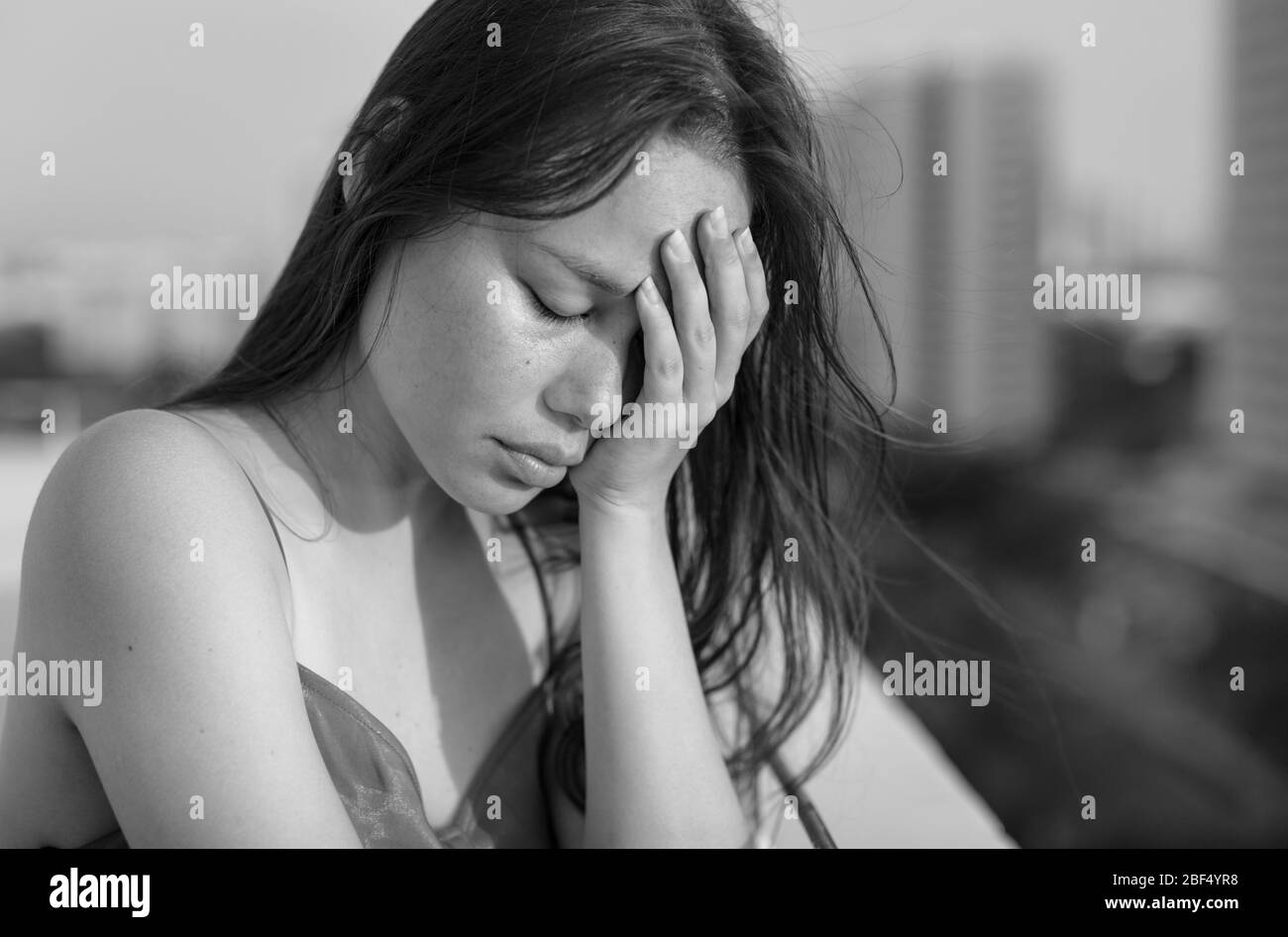 A woman standing on her balcony window depressed and unhappy. black and white. Stock Photo