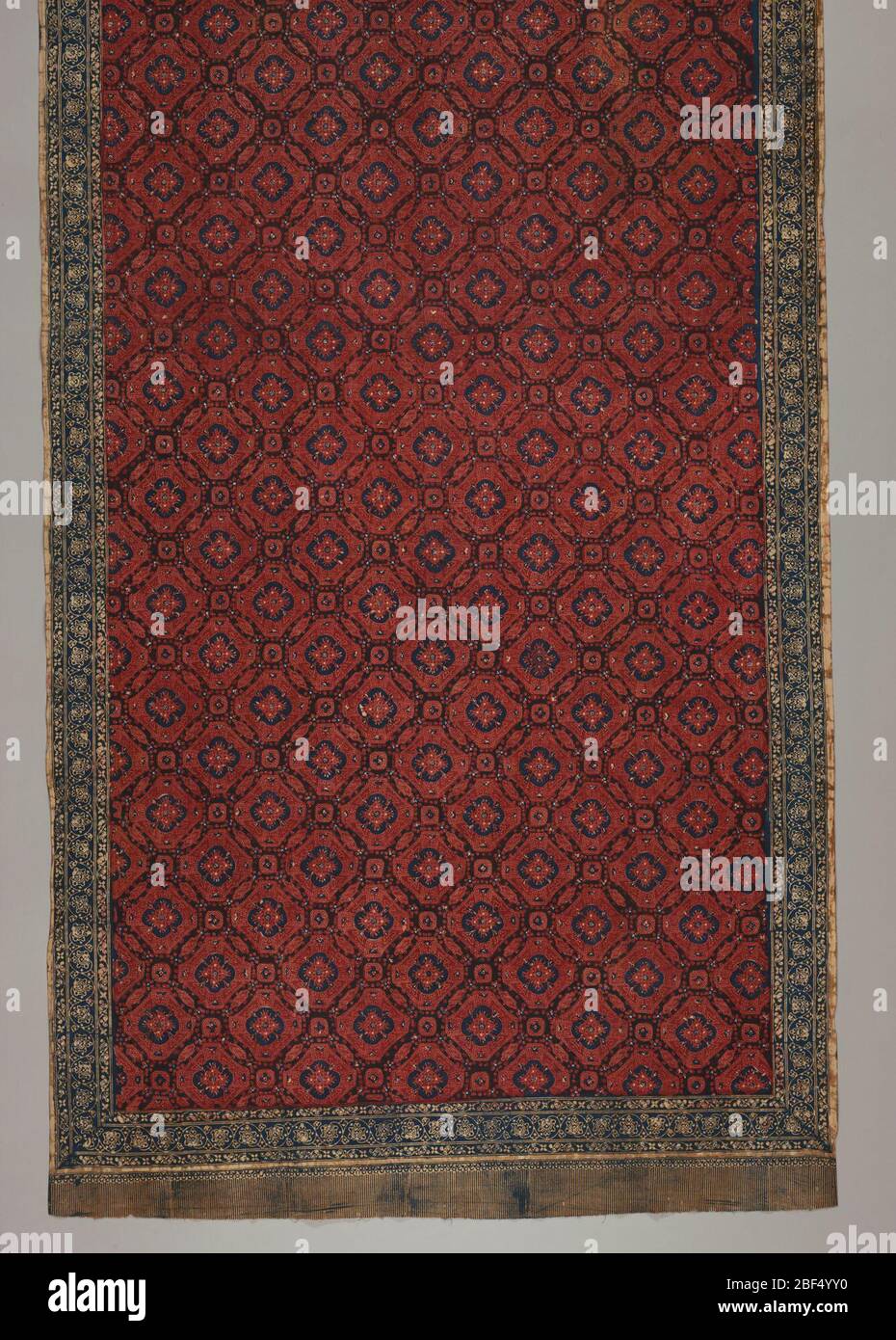Sarong. Red and blue batik sarong. Shows 'ceplokkan' pattern: flowers or blossoms, symmetrically distributed over surface, stylized, star-like,and contained within a geometric shape. Borders show batiked on fringe. Stock Photo