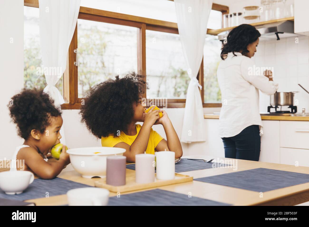 Mother cooking for her two children waiting for lunch. Single mom concept. Stock Photo
