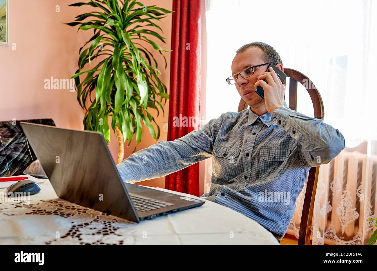 Man talking with phone while working from home office. Stock Photo