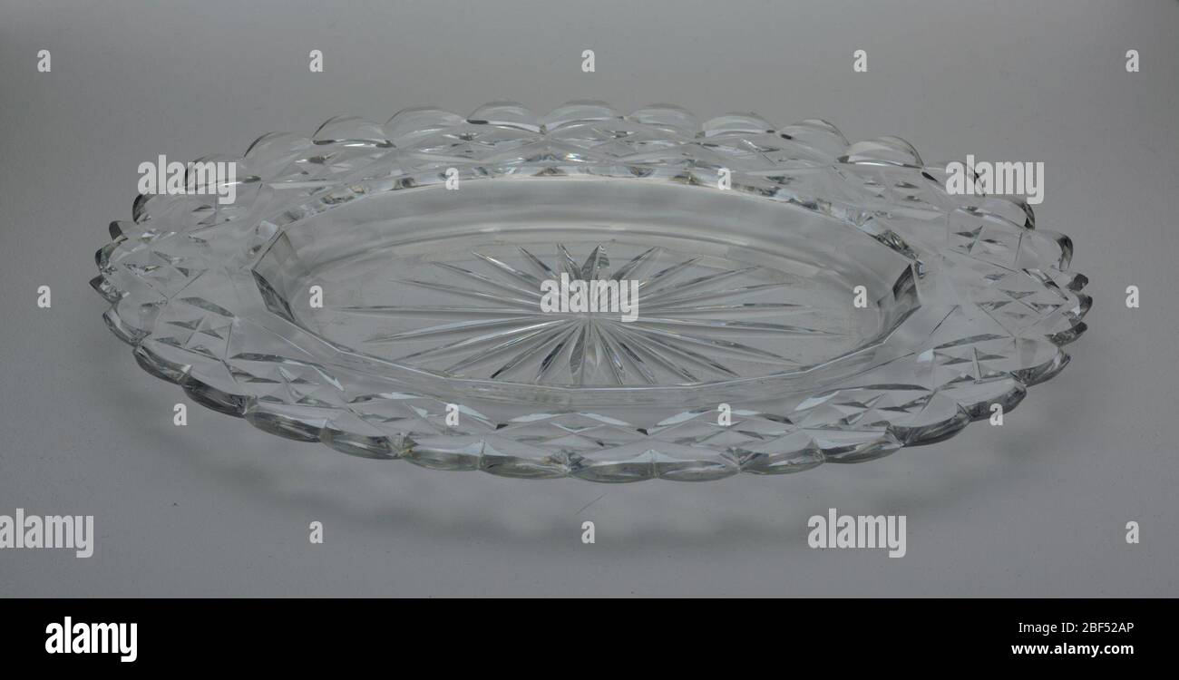 Dish. Oval dish with wide rim scalloped at the edge, star cut at center, cavetto with facets, the rim cut with flat diamond pattern, glass clear and heavy. Stock Photo