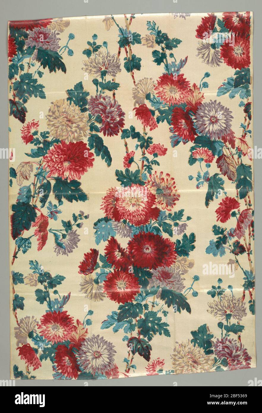 Textile. Allover design of asters in red, purple, blue and green on an off-white ground. Stock Photo