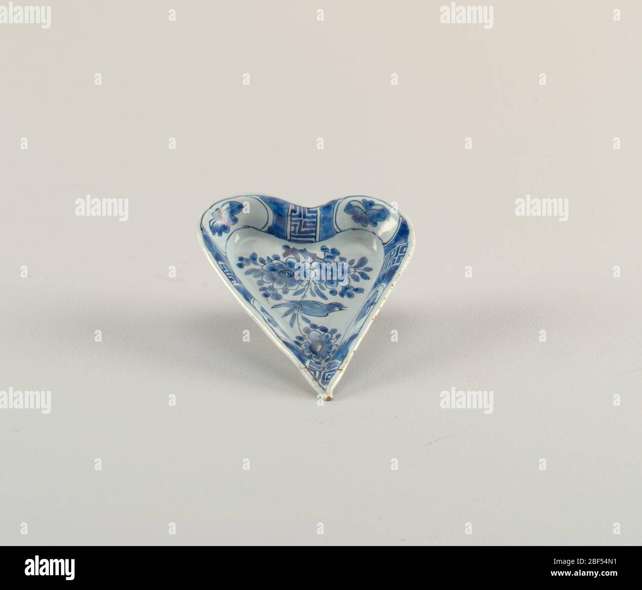 Dish. Heart-shaped dish on short foot rim with slightly flaring sides; painted inunderglaze blue on white with birds and flowers in center, on sides with alternating panels of flowers and pseudo-Chinoiserie characters. Stock Photo
