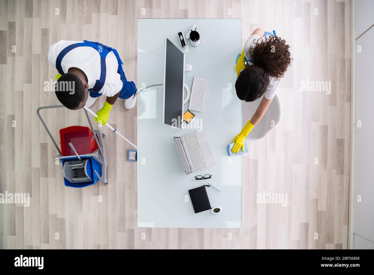 Young Male And Female Cleaners Cleaning Office Stock Photo