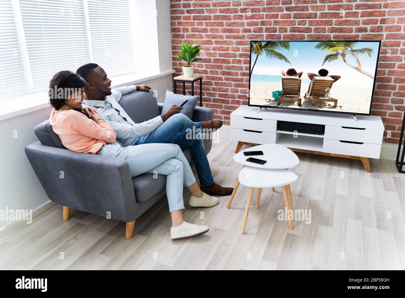 Rear View Of A Couple Watching Movie On Television At Home Stock Photo