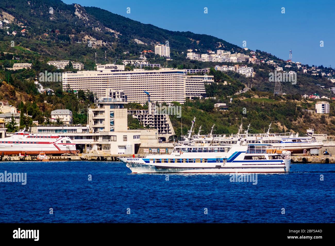 Yalta, Crimea, Russia - 05 October 2015: Marine pleasure ship in the Yalta Bay on the background of the Intourist Hotel Stock Photo