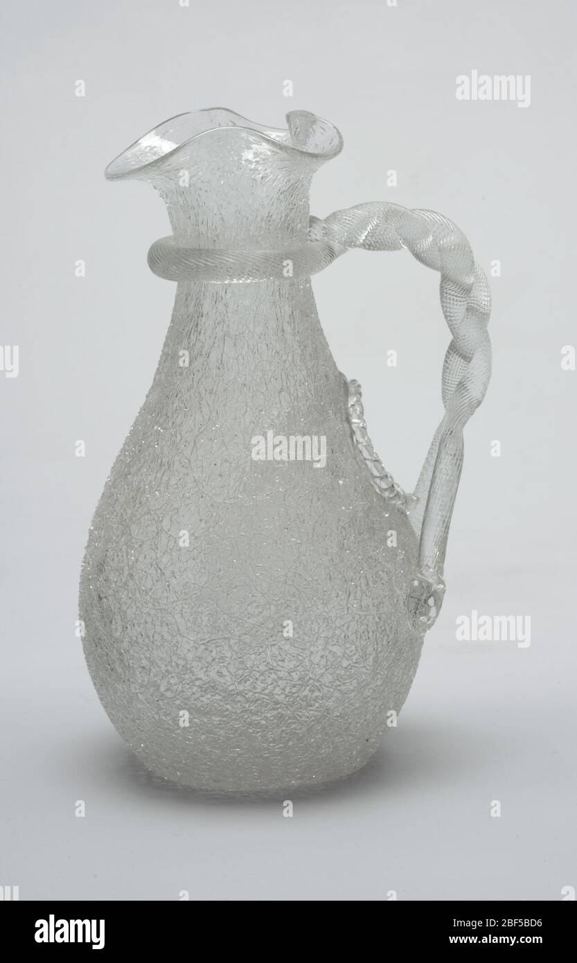 Pitcher. Of clear 'ice' or 'overshot' glass, the rough-surfaced ovoid body tapering to slender neck flaring to mouth pinched to form wide spout; handle formed of spiral-textured rod looped around neck, twisted and attached to body below oval opening of indented well (f Stock Photo