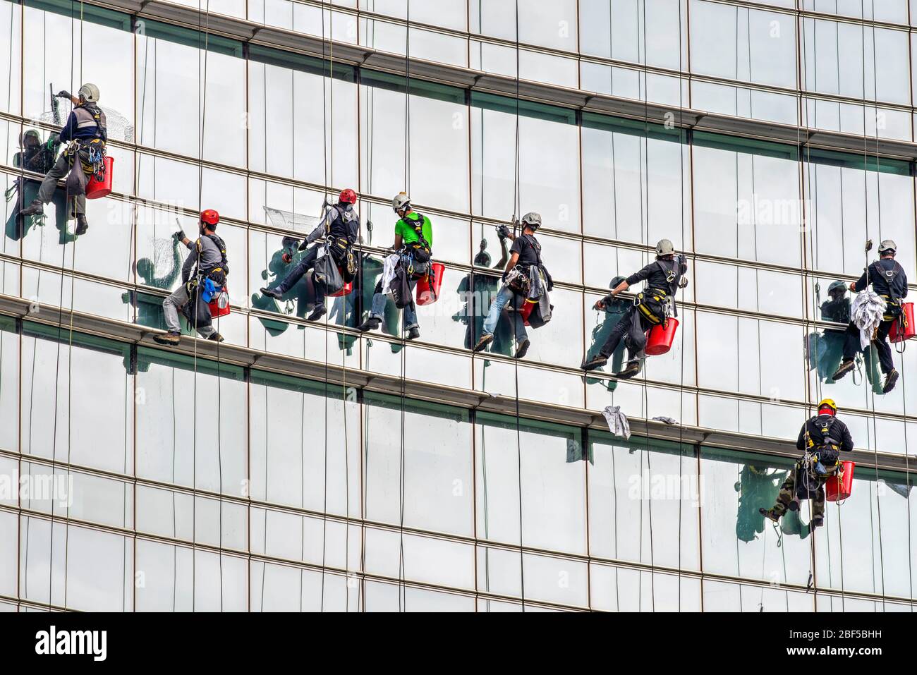 High rise window cleaners at work on the glassy facade of a skyscraper in Milan, Italy Stock Photo