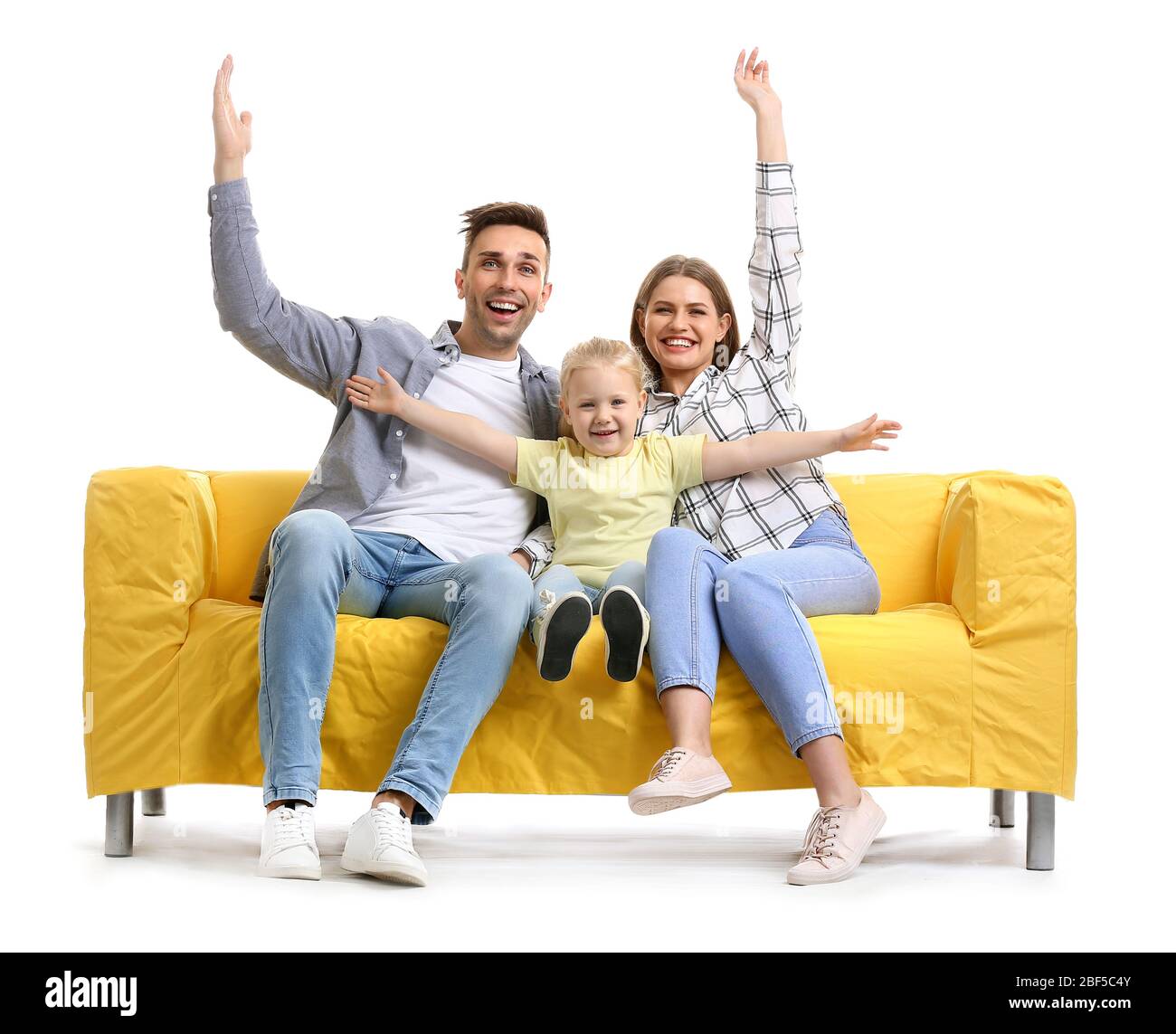 Happy young family sitting on sofa against white background Stock Photo