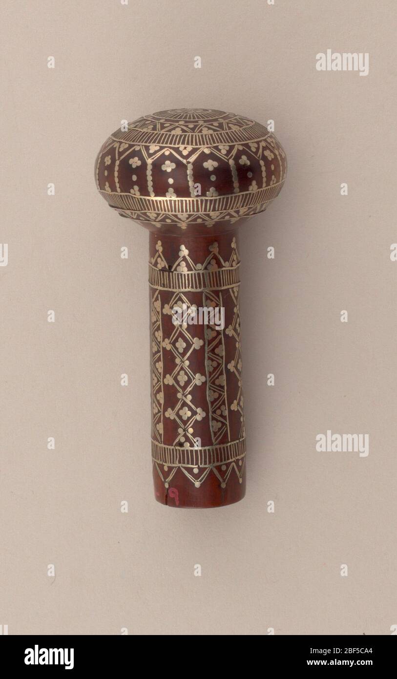 Cane handle. Small round knob, slightly flattened, set on short stem; wood inlaid in silver in completely conventionalized design; formed of small lines, dots in circular pattern or perpendicular pattern on stem. Stock Photo