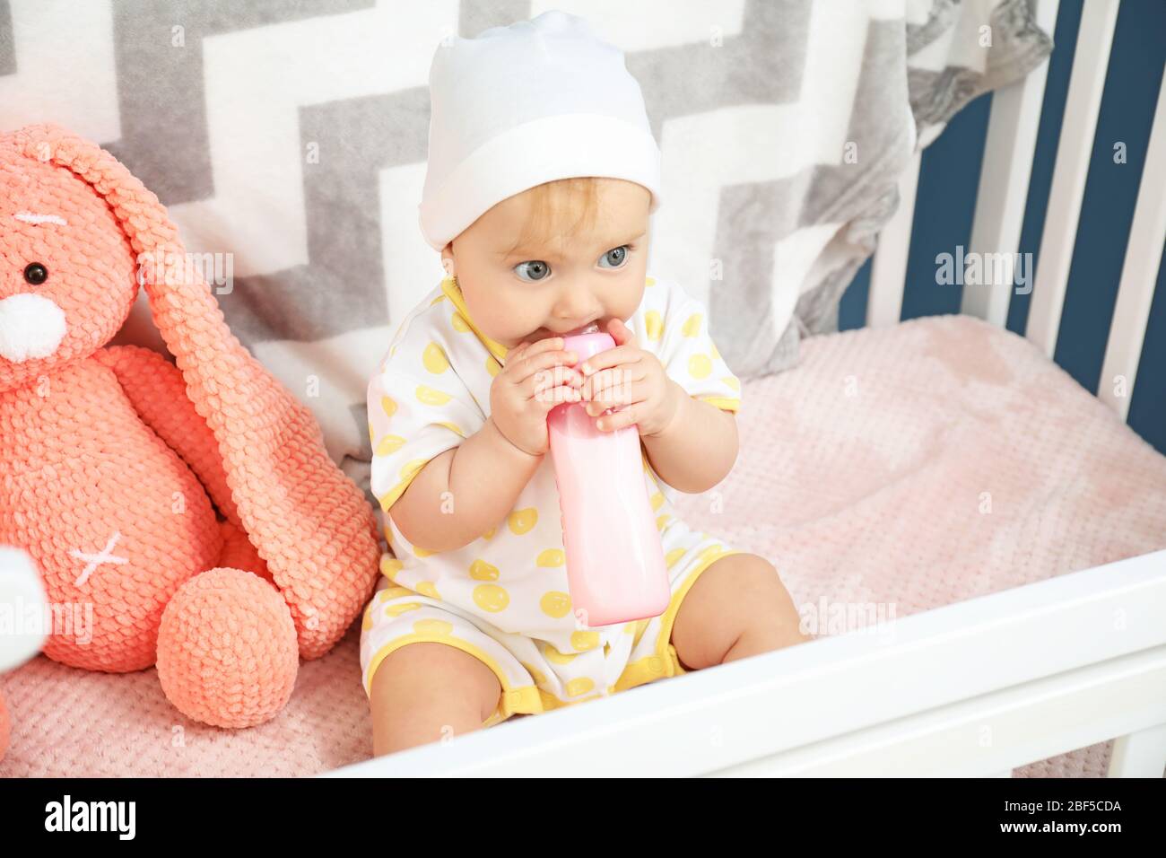 Cute baby drinking milk from bottle in crib Stock Photo Alamy