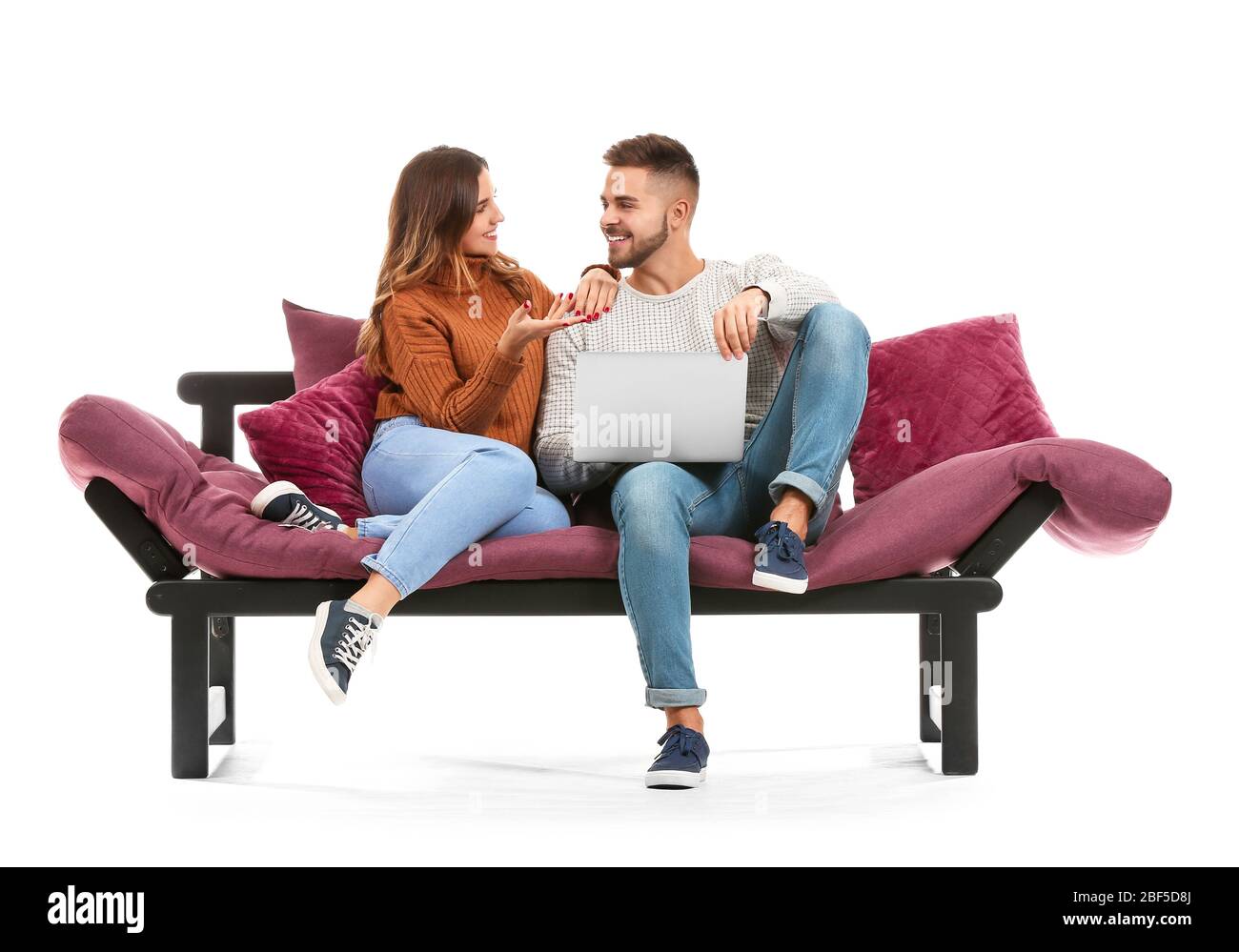 Young couple with laptop sitting on sofa against white background Stock ...